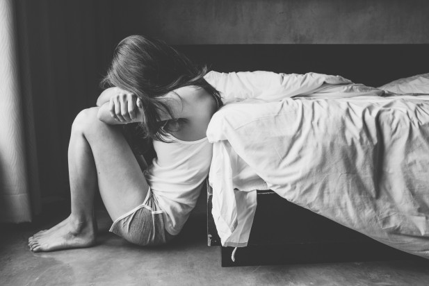 Portrait of depressed woman sitting alone on the floor in the bedroom.